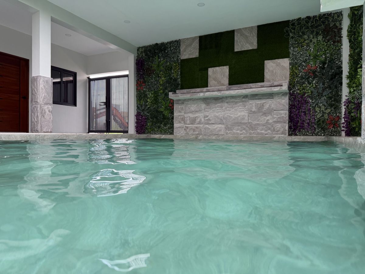 The turquoise spring pool filling a high-ceilinged hall, a living wall and stone waterfall along the far side