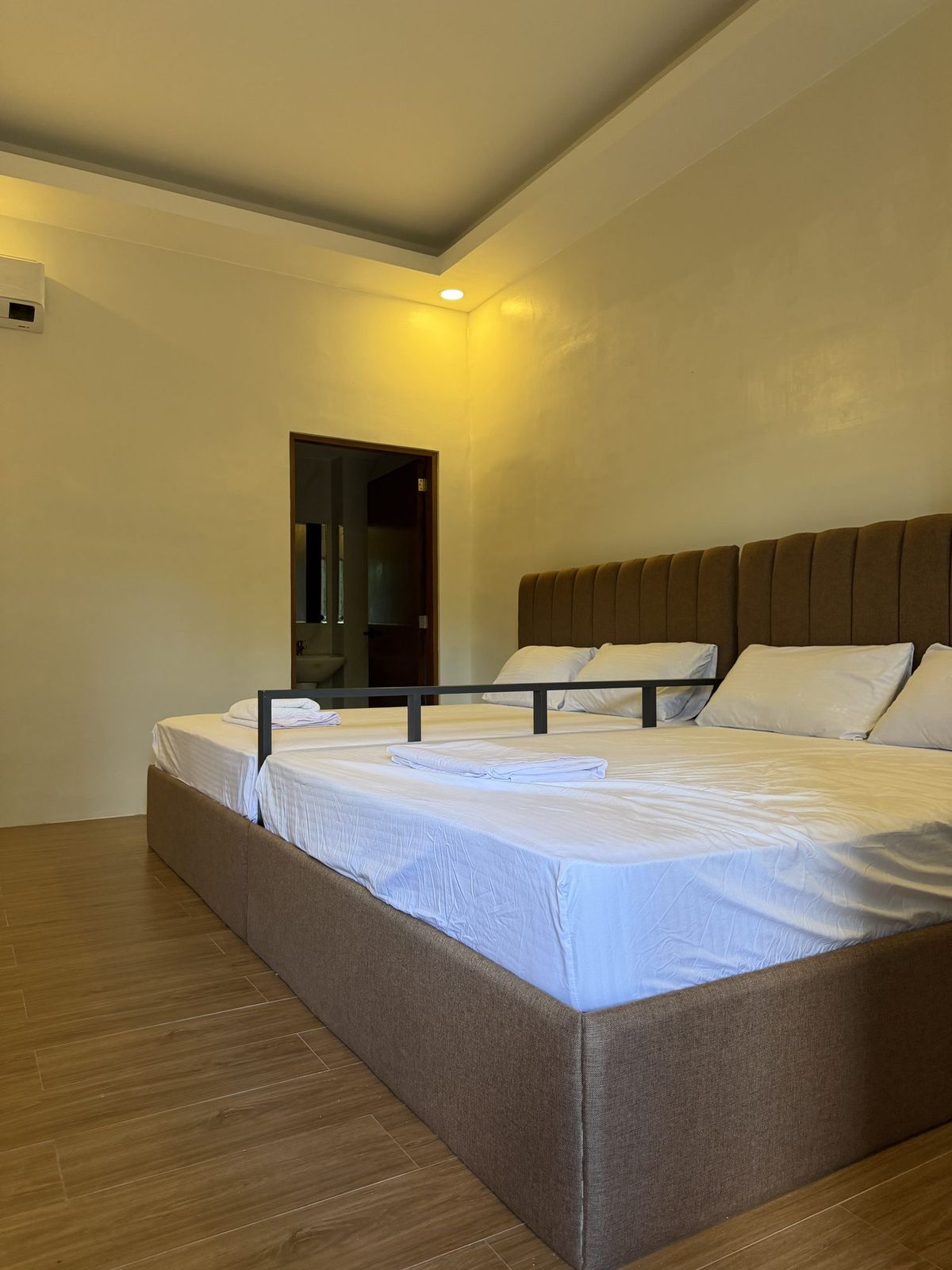 A second double room lit by a warm bedside lamp on a wood floor